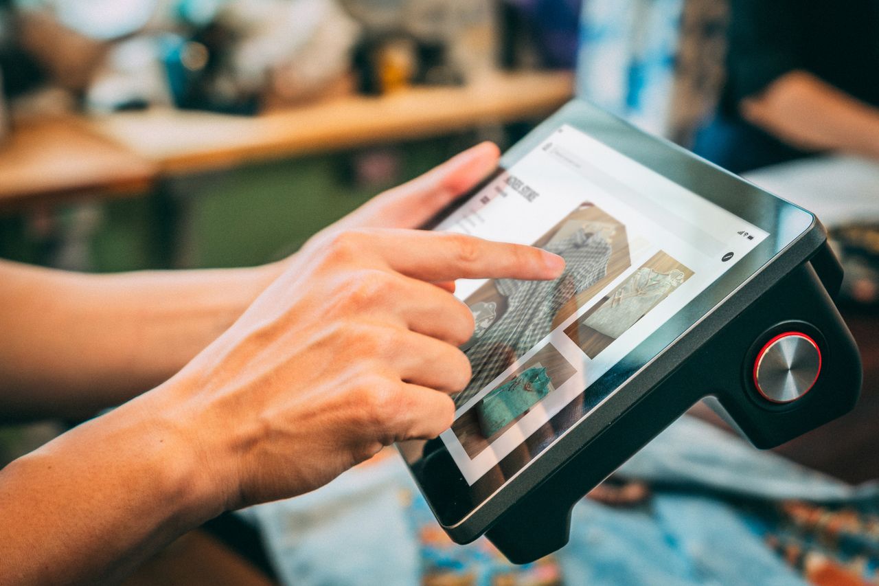Vue rapprochée de mains interagissant avec un appareil à écran tactile, mettant en valeur du contenu numérique.